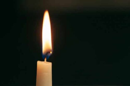 uma unica vela acesa isolada com fundo preto